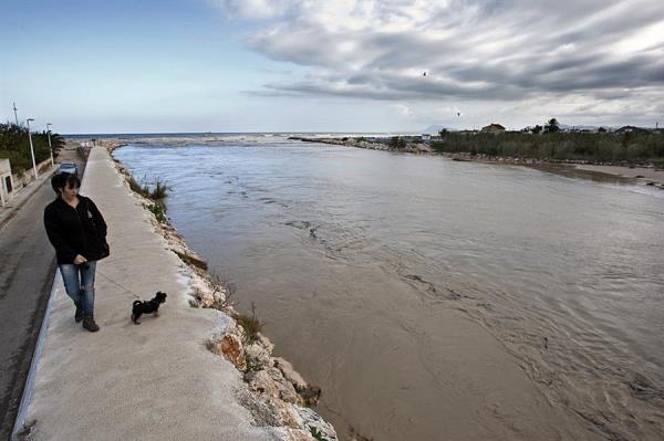 Una mujer pasea con su perro en la desembocadura del río Serpis